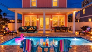 A pool area with lounge chairs, a dining table, and a pink flamingo float.