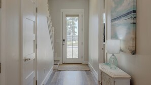 A hallway with a white door, a staircase, and a painting on the wall.