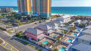 A coastal residential area with multiple buildings, including a prominent hotel with a swimming pool and a view of the ocean.