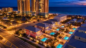 A resort with multiple swimming pools, beachfront properties, and high-rise buildings in the background.