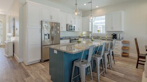 A modern kitchen with white cabinets, stainless steel appliances, and a central island with bar stools.