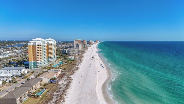 A coastal cityscape with a long sandy beach, high-rise hotels, and a clear blue ocean.