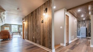 Un vaste espace de vie avec un lambris en bois, un canapé et un réfrigérateur à l’arrière-plan.