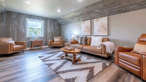 Un salon moderne avec un plafond en bois, des canapés en cuir, une table basse et une grande fenêtre.