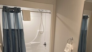 A modern bathroom with a bathtub, toilet, and vanity. - Acadia Villas!  3A Olivia.  A private neighborhood nestled in the woods. (Trenton)