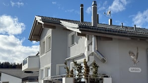 Een meerlaags gebouw met een grijze gevel, een balkon en een schoorsteen.