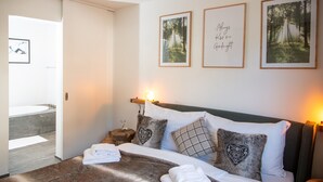 Een hotelkamer met een bed, nachtkastje, wandlamp en foto's in een lijst aan de muur.