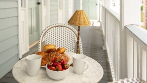 A covered porch with a table set for breakfast, including croissants, strawberries, and a cup. - Newly Restored Historic Home, Close to King! (Charleston)