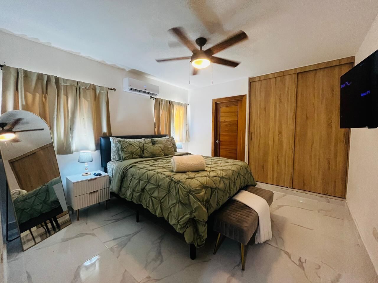 Une chambre à coucher avec un lit, une table de chevet, une lampe et un ventilateur de plafond.