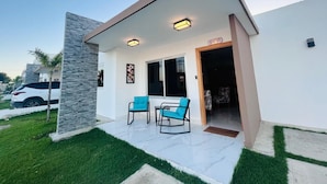 Ein modernes Haus mit einer Terrasse, ausgestattet mit zwei blauen Stühlen und einem kleinen Tisch.