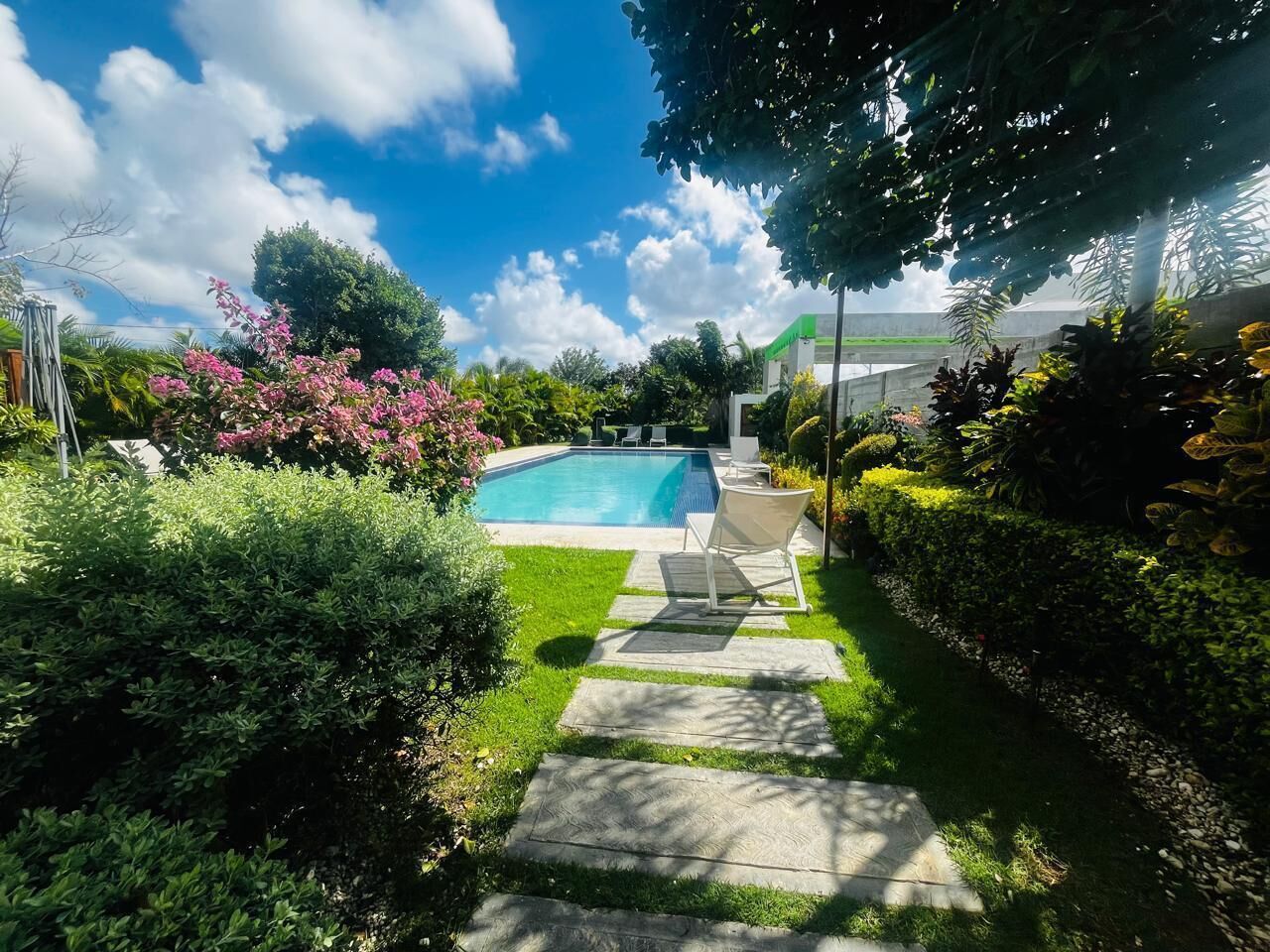 Ein Garten mit Schwimmbecken, einem Kiesweg und üppiger Bepflanzung.