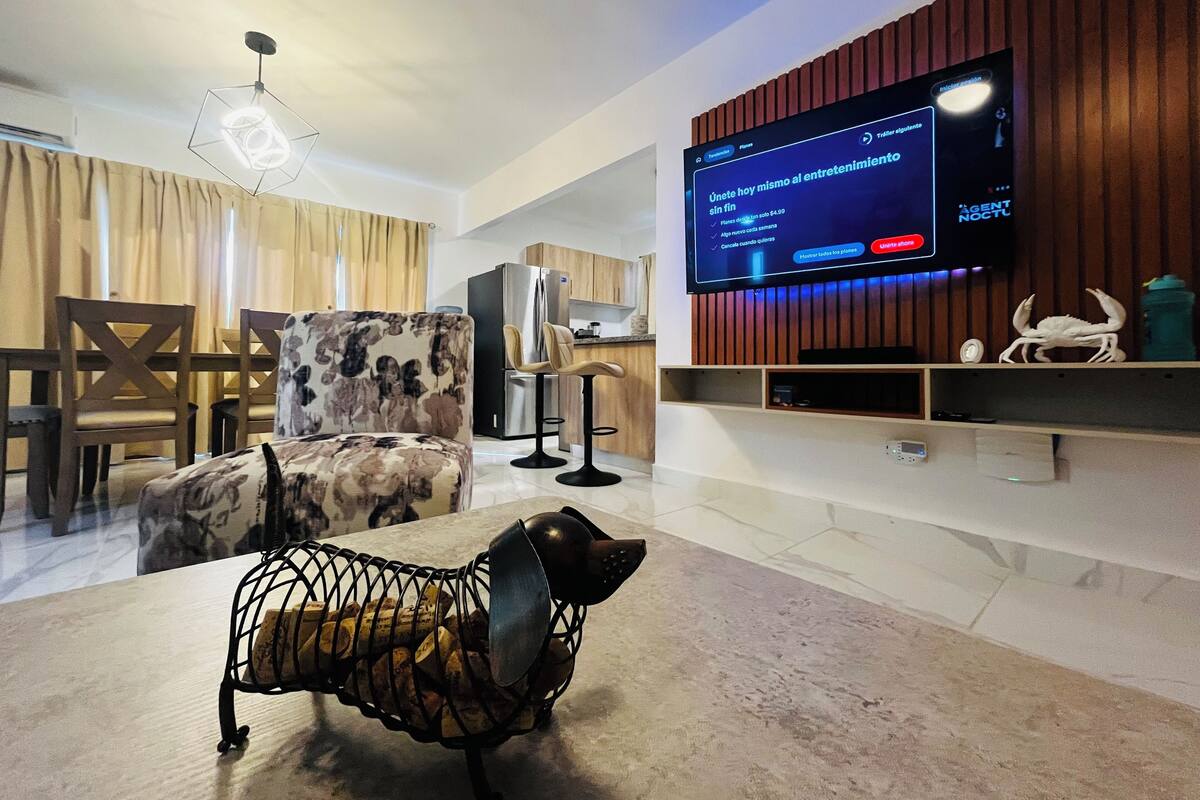 Een moderne woonkamer met een televisie, een eethoek en een keuken.