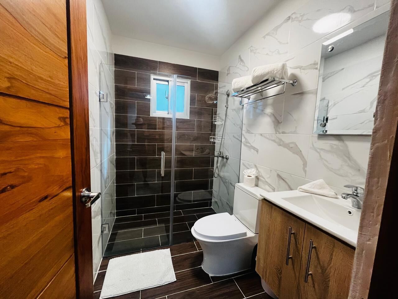 Une salle de bain avec une douche à parois de verre, des toilettes et un lavabo.