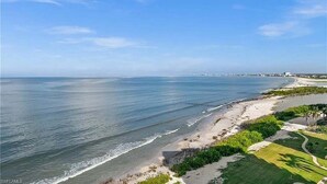 A coastal landscape with a beach, a clear sky, and a distant city skyline. - Private Balcony, Ocean View, Steps to the Beach - Sunsets & Sanddollars - Roelens (Fort Myers Beach)