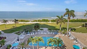 A resort with a pool, beach view, and palm trees. - Private Balcony, Ocean View, Steps to the Beach - Sunsets & Sanddollars - Roelens (Fort Myers Beach)