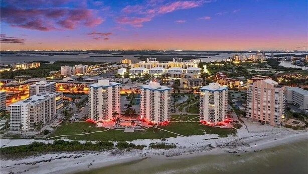A coastal cityscape with high-rise buildings, a beach, and a marina. - Private Balcony, Ocean View, Steps to the Beach - Sunsets & Sanddollars - Roelens (Fort Myers Beach)