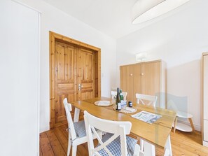 Uma sala de jantar com mesa de madeira, cadeiras brancas e um armário de madeira.