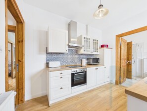 A modern kitchen with white cabinetry, a tiled backsplash, a microwave, and a built-in oven.
