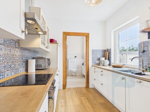 A modern kitchen with a wooden countertop, a built-in microwave, and a window providing natural light.