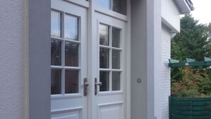 En vit dubbeldörr med glaspaneler och ett litet trappsteg som leder upp till entrén.