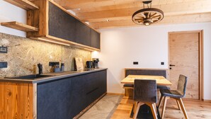 A modern kitchen with a wooden countertop, built-in cabinets, and a dining area with a table and chairs. - Apartment 'Wiese' with Mountain View, Private Terrace and Wi-Fi (Sesto)