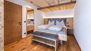 Ein Schlafzimmer mit einem hölzernen Bett, einer Bank, einem Spiegel und einer Holzzahl.