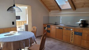 A kitchen with wooden cabinets, a dining table with a white tablecloth, and a skylight.