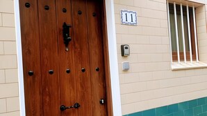 Una puerta de madera con un picaporte metálico, una ventana con barrotes verticales y un cartel sobre la puerta que dice 'Rua Rinate No 11'.