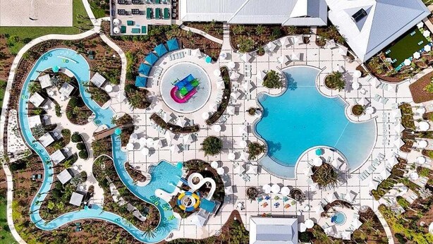 An aerial view of a resort with multiple swimming pools, a water park, and various lounge areas. - Brand New Home at Windsor Cay Resort with Lazy River (Clermont)