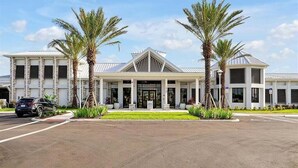 A modern building with a symmetrical facade, large windows, and a central entrance. - Brand New Home at Windsor Cay Resort with Lazy River (Clermont)