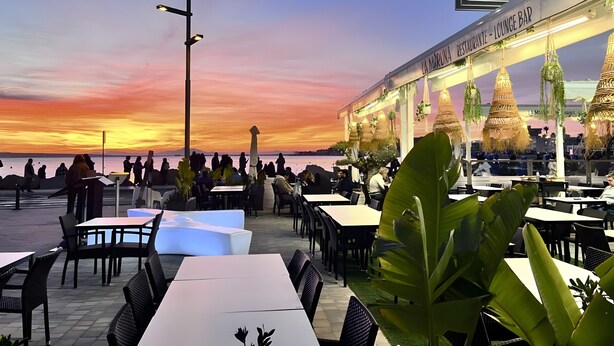 An outdoor dining area with tables and chairs, a street lamp, and a restaurant named 'La Moruna Restaurante - Lounge Bar' with hanging plants. - Holiday Home 'Horizon Oasis' with Sea View, Wi-Fi and Air Conditioning (Santa Pola)