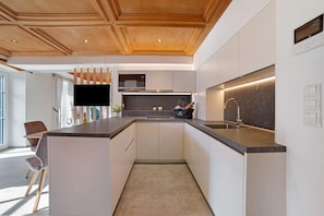 A modern kitchen with a wooden ceiling, a built-in microwave, and a sink.