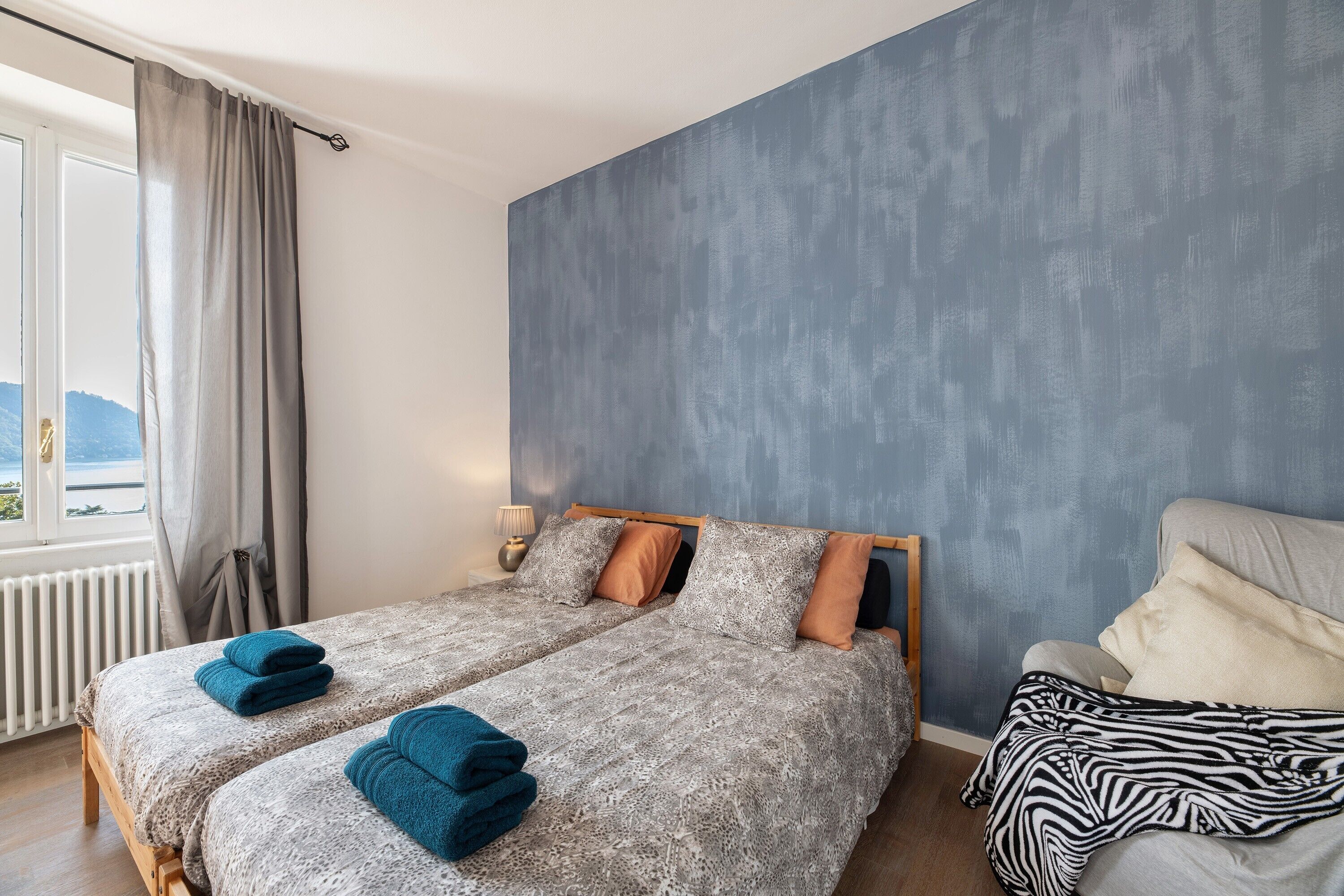 Une chambre avec deux lits, une vue sur l’extérieur et une grande fenêtre avec des rideaux.