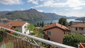 Un balcon avec vue sur un lac, des montagnes et une ville.