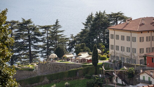 Un hôtel situé sur la côte, doté d’une terrasse avec vue sur la mer, d’un jardin et d’un bâtiment traditionnel avec un toit en tuiles.