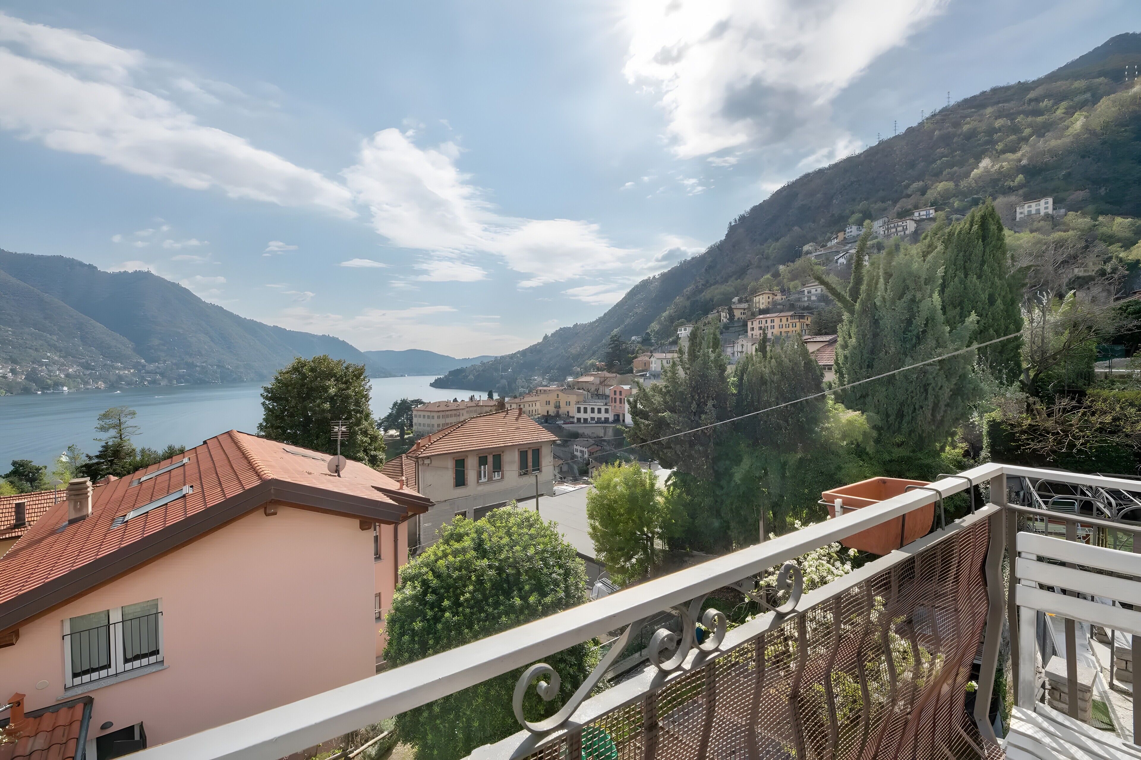 A balcony with a view of a lake, buildings, and hills.