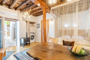 Una habitación acogedora con una mesa de madera, un sofá, una lavadora y una cama con dosel.
