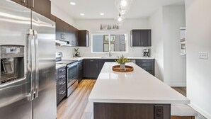 Uma cozinha moderna com armários escuros, eletrodomésticos de aço inoxidável e uma ilha central.