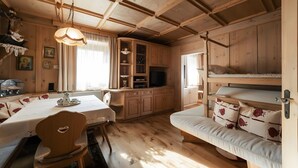 Un interior de madera con una mesa de comedor, sillas, un sofá y una televisión.