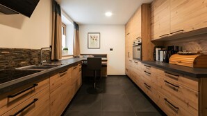 Una cocina moderna con armarios de madera, encimera negra y horno empotrado.