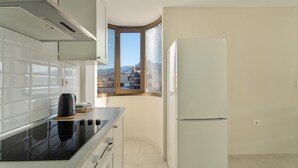 A kitchen with a stove, a refrigerator, and a window with a view of buildings. - Vacation 'Ático Home' with Sea View, Balcony and Wi-Fi (Los Cristianos)