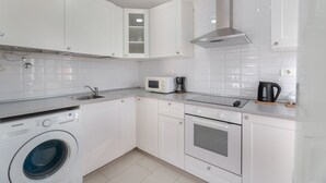 A modern kitchen with white cabinets, a built-in microwave, a coffee maker, and a washing machine. - Vacation 'Ático Home' with Sea View, Balcony and Wi-Fi (Los Cristianos)