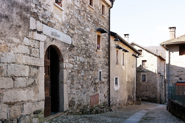 A stone building with an arched doorway, a sign above the door, and a narrow cobblestone street.