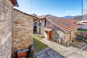 A stone building with a tiled roof, a small garden, and a patio area with outdoor seating.