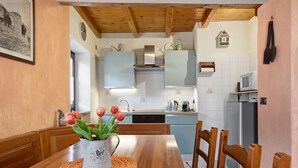 A kitchen with wooden cabinets, a dining table with chairs, a refrigerator, and a microwave.