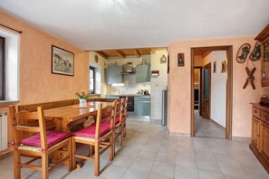 A kitchen with wooden cabinets, a dining table with chairs, and a hallway leading to another room. - Apartment 'Tillier' with Mountain View and Wi-Fi (Fenis)