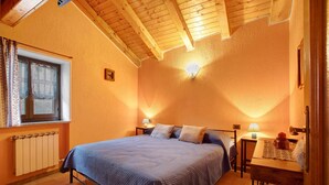 A bedroom with a bed, a window with curtains, a bedside table with a lamp, and a radiator.