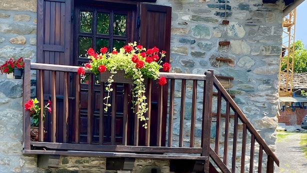 A stone building with a wooden balcony, a door, and a staircase.