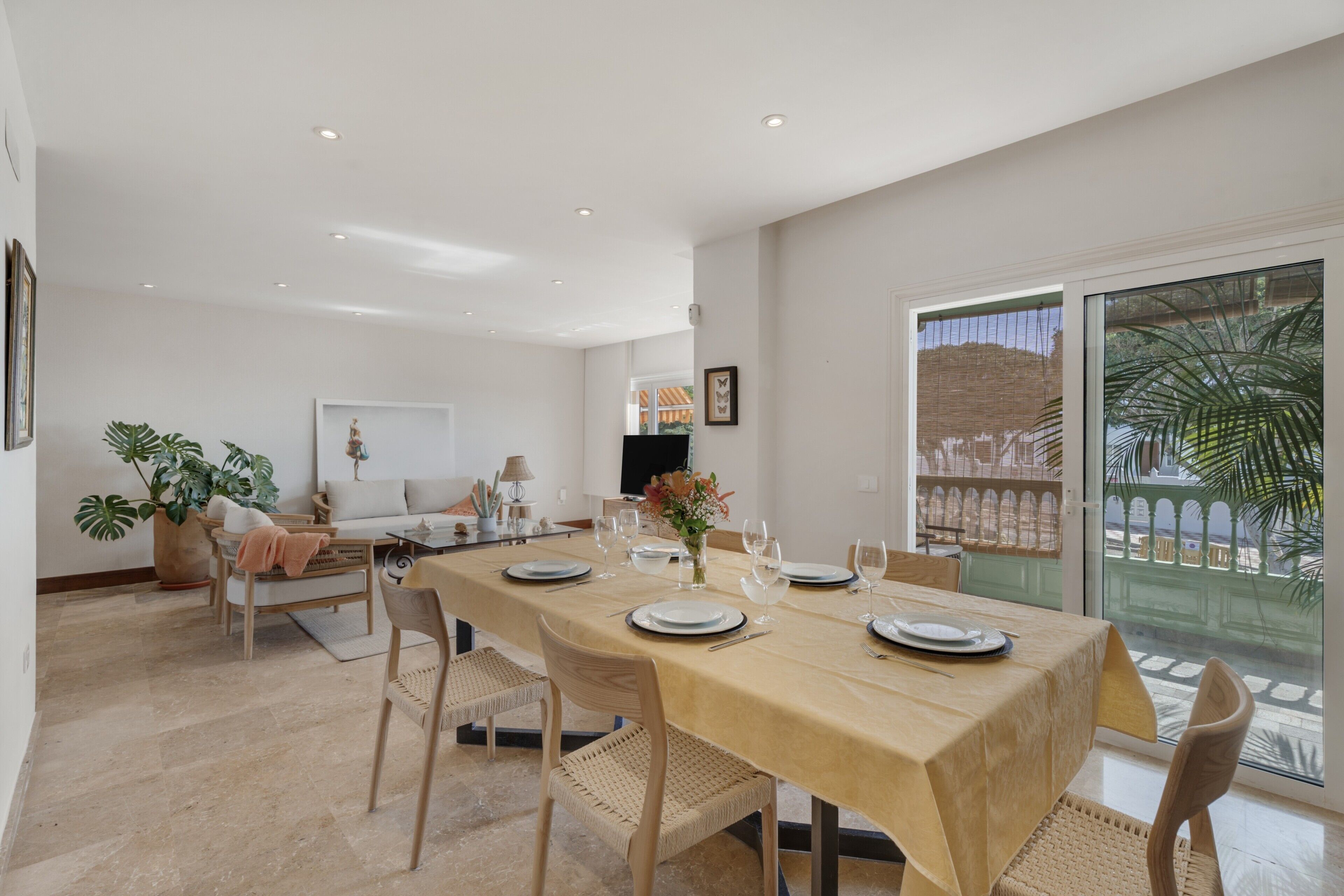 Un comedor con una mesa larga, sillas y vistas a un patio a través de un ventanal.
