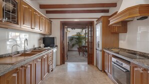 A kitchen with wooden cabinets, granite countertops, and a view to a dining area. - Vacation Villa 'Spinnaker Playa' with Sea View, Private Terrace and Wi-Fi (Santiago del Teide)